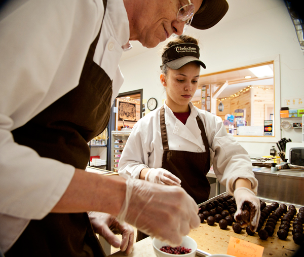 Livia Worley, 20, right, helps Dale Anderson coat truffles in chocolate at Confections with Convictions. 