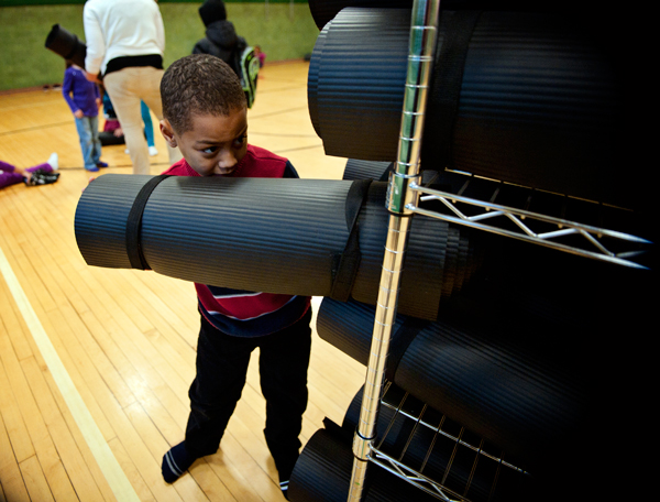 A young student puts his yoga mat back as part of The Developing the Community School Project.